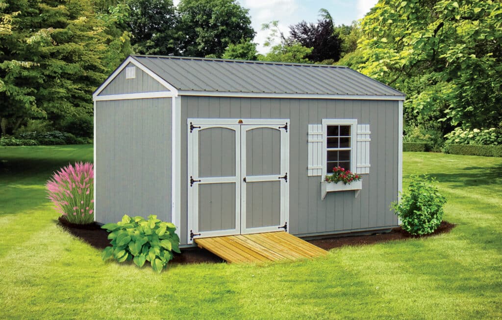 gray garden shed with white trim wooden ramp and garden around it as well as flower box under window