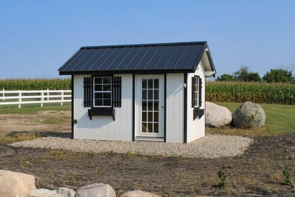 Shed on Foundation in Indiana Corn field. White siding and door with black roof and trim