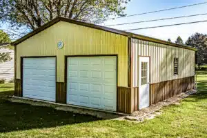 Two-tone tan and brown metal garage with white double doors and clock above